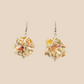 Pair of white geometric origami earrings with a floral pattern on a beige background
