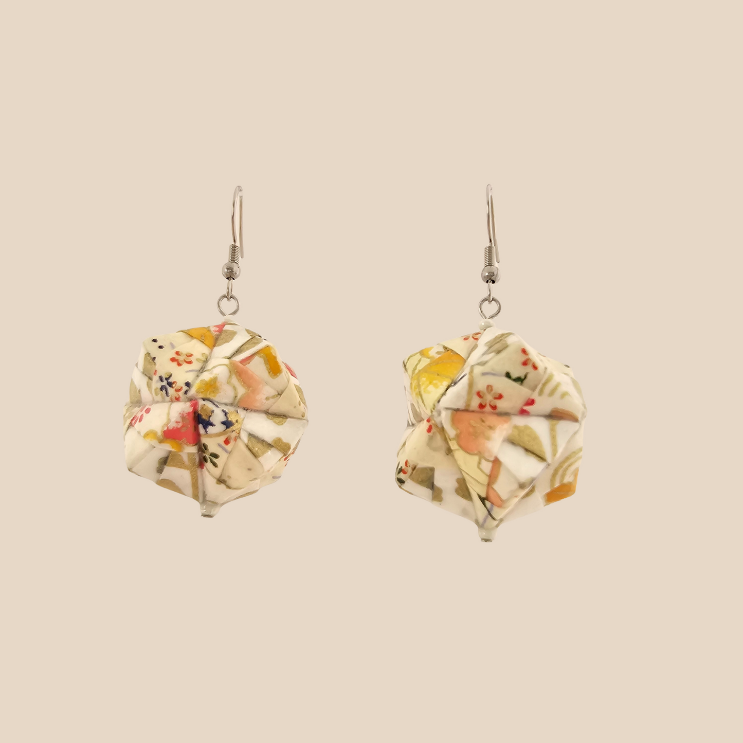 Pair of white geometric origami earrings with a floral pattern on a beige background