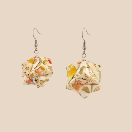 Pair of white geometric origami earrings with a floral pattern on a beige background