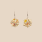 Pair of white geometric origami earrings with a floral pattern on a beige background