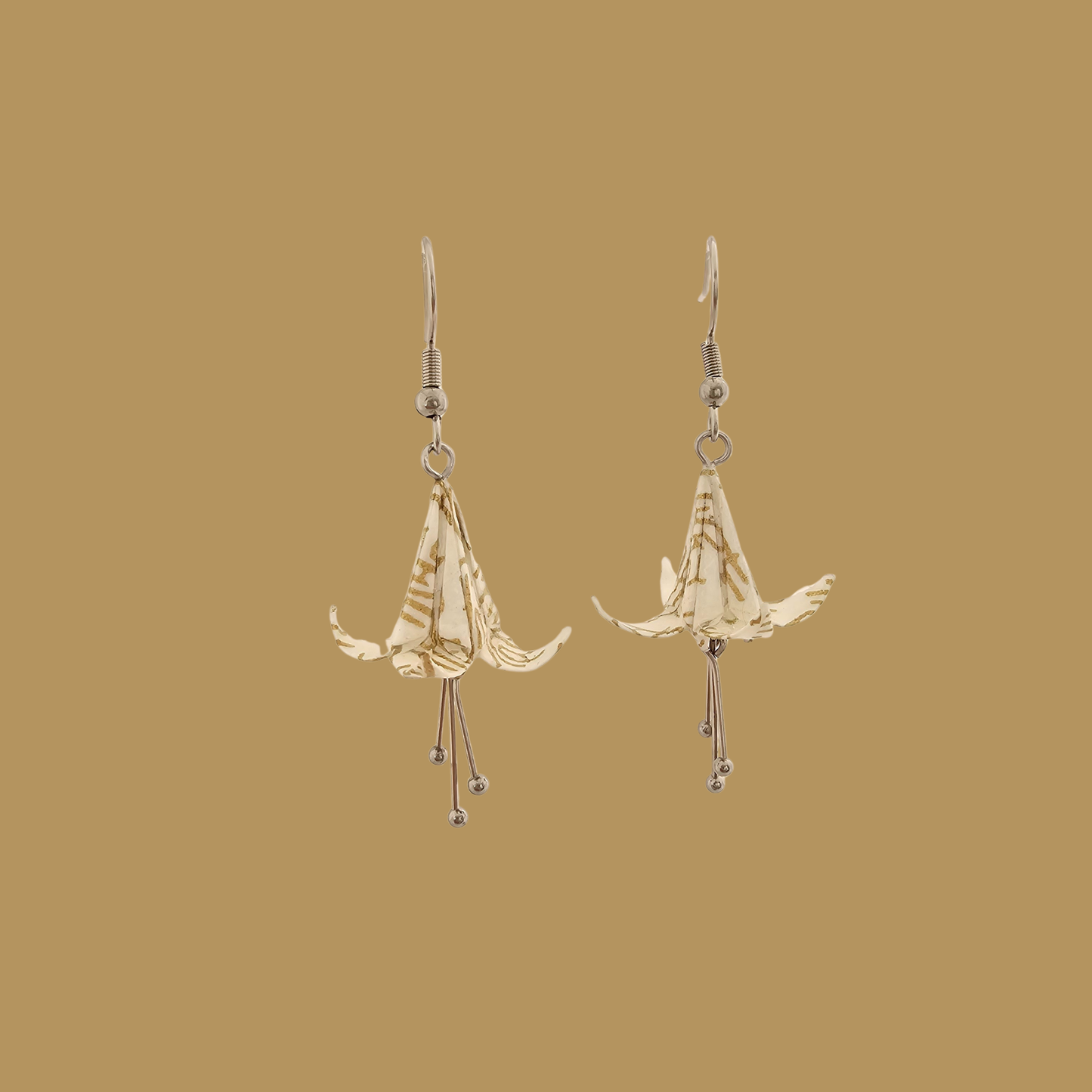 White and gold origami lily earrings with a floral and geometric pattern on a beige background