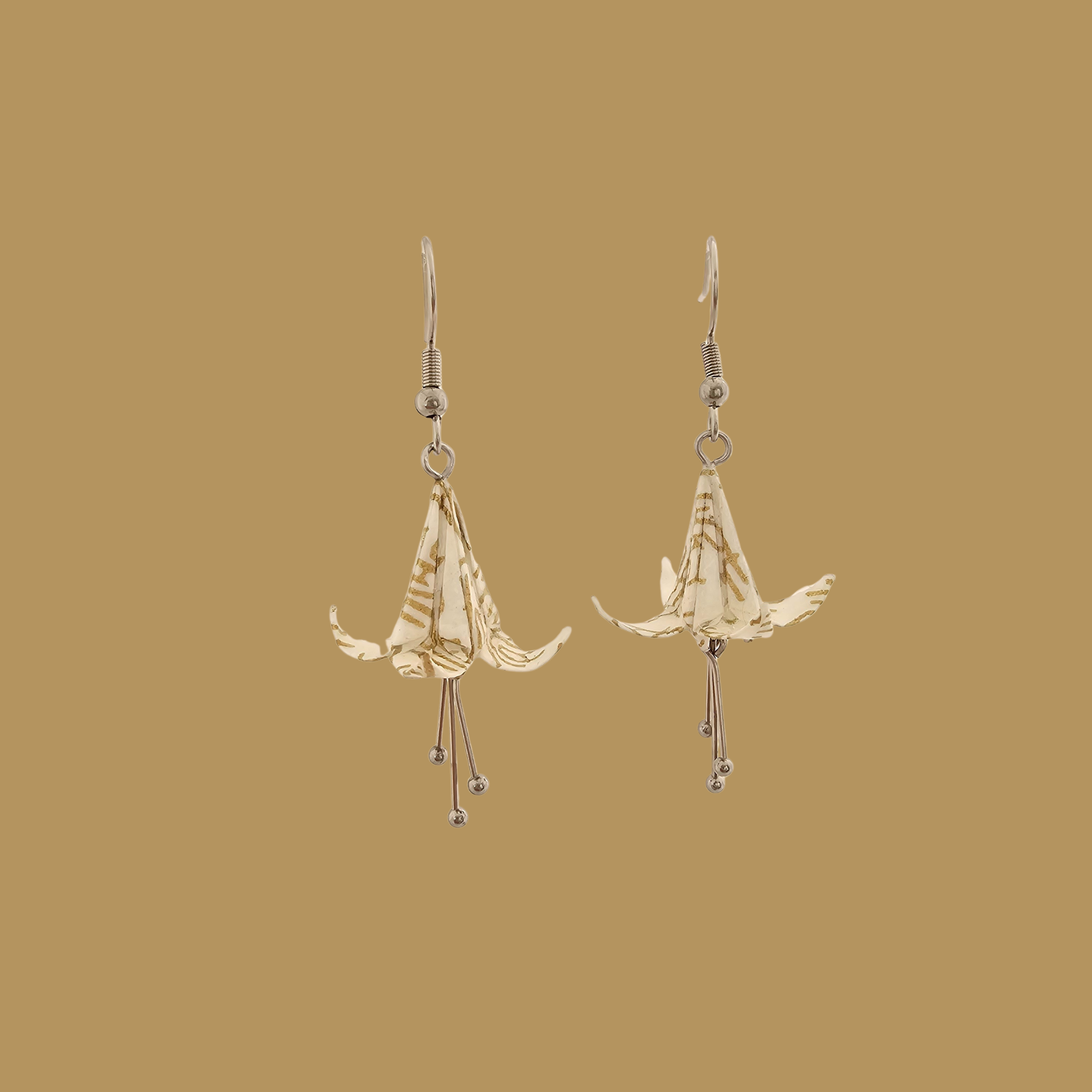 White and gold origami lily earrings with a floral and geometric pattern on a beige background
