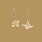 White and gold origami lily earrings with a floral and geometric pattern on a beige background