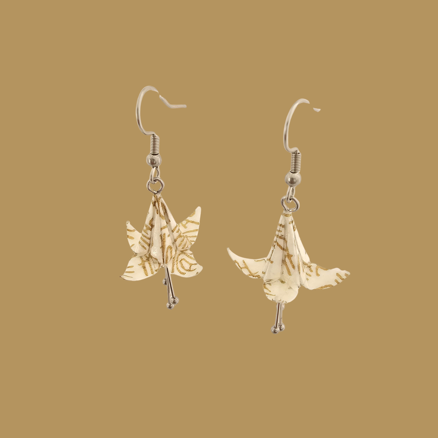 White and gold origami lily earrings with a floral and geometric pattern on a beige background