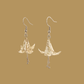 White and gold origami lily earrings with a floral and geometric pattern on a beige background