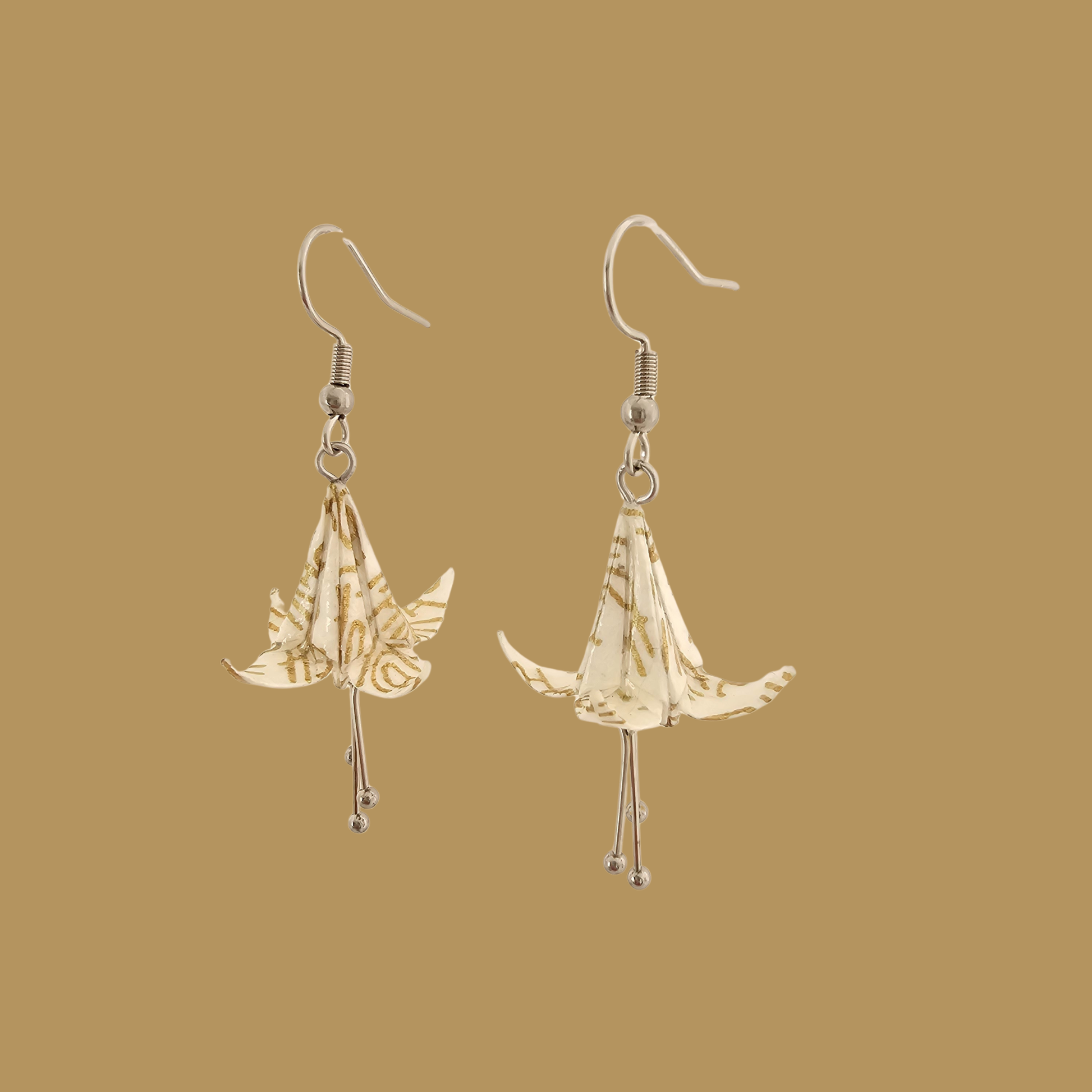 White and gold origami lily earrings with a floral and geometric pattern on a beige background