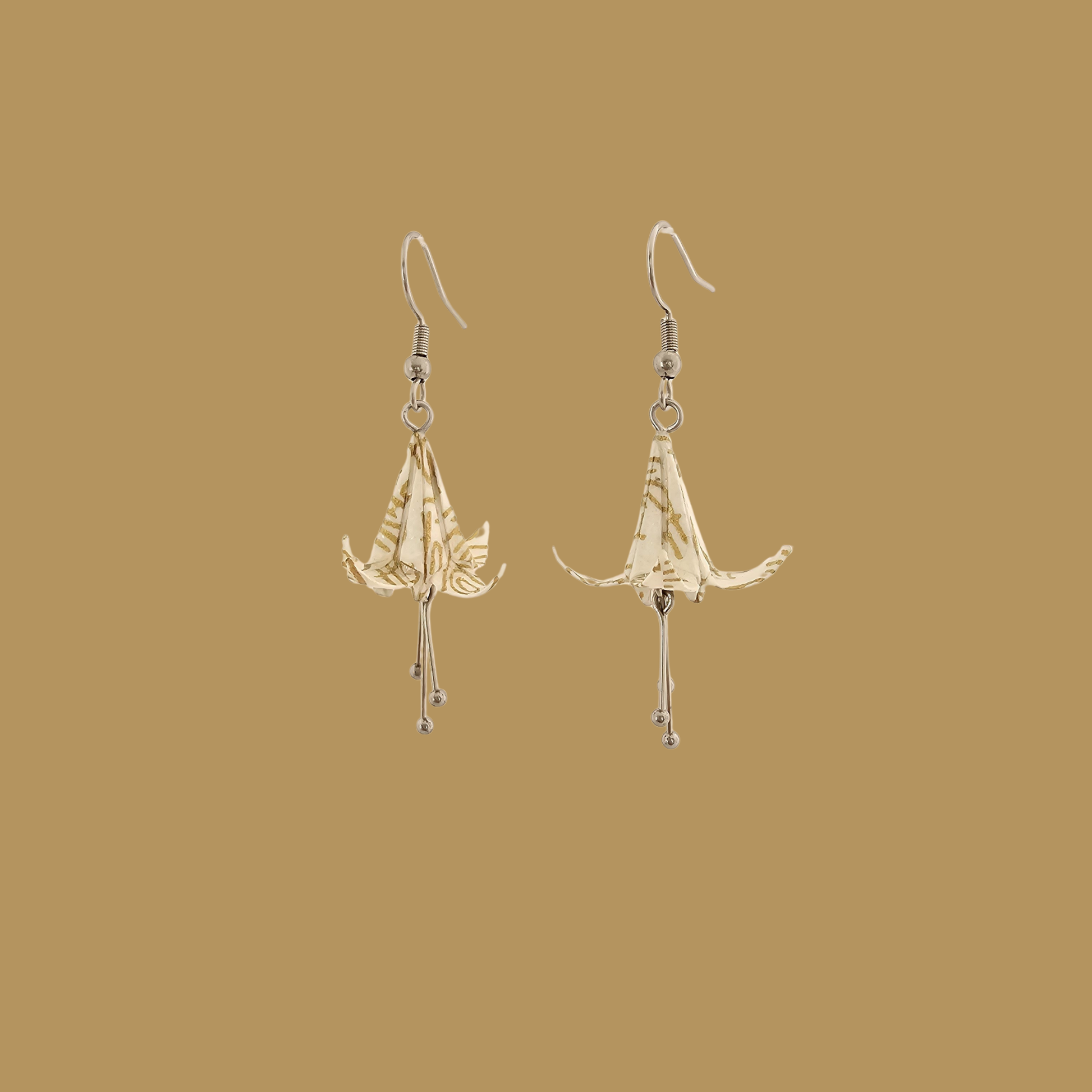 White and gold origami lily earrings with a floral and geometric pattern on a beige background