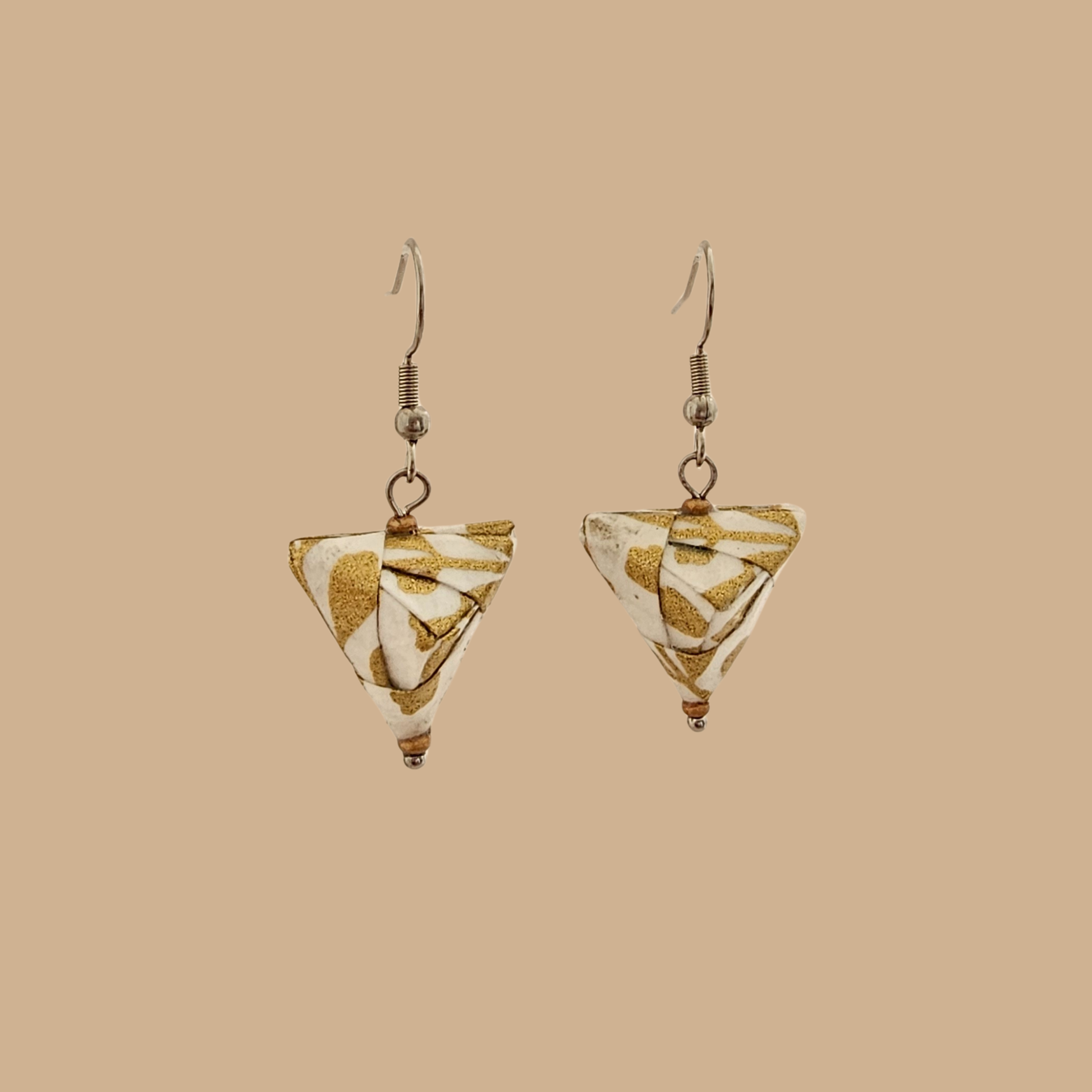 White and Gold triangle geometric origami earrings with a floral and geometric pattern on a beige background