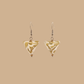 White and Gold triangle geometric origami earrings with a floral and geometric pattern on a beige background
