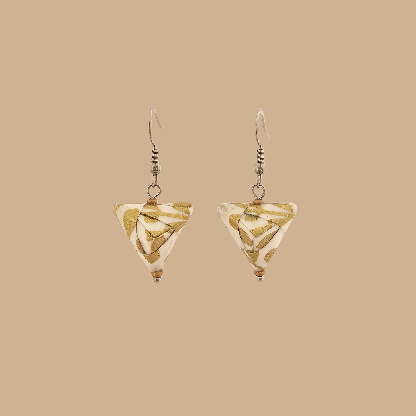 White and Gold triangle geometric origami earrings with a floral and geometric pattern on a beige background