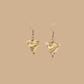 White and Gold triangle geometric origami earrings with a floral and geometric pattern on a beige background