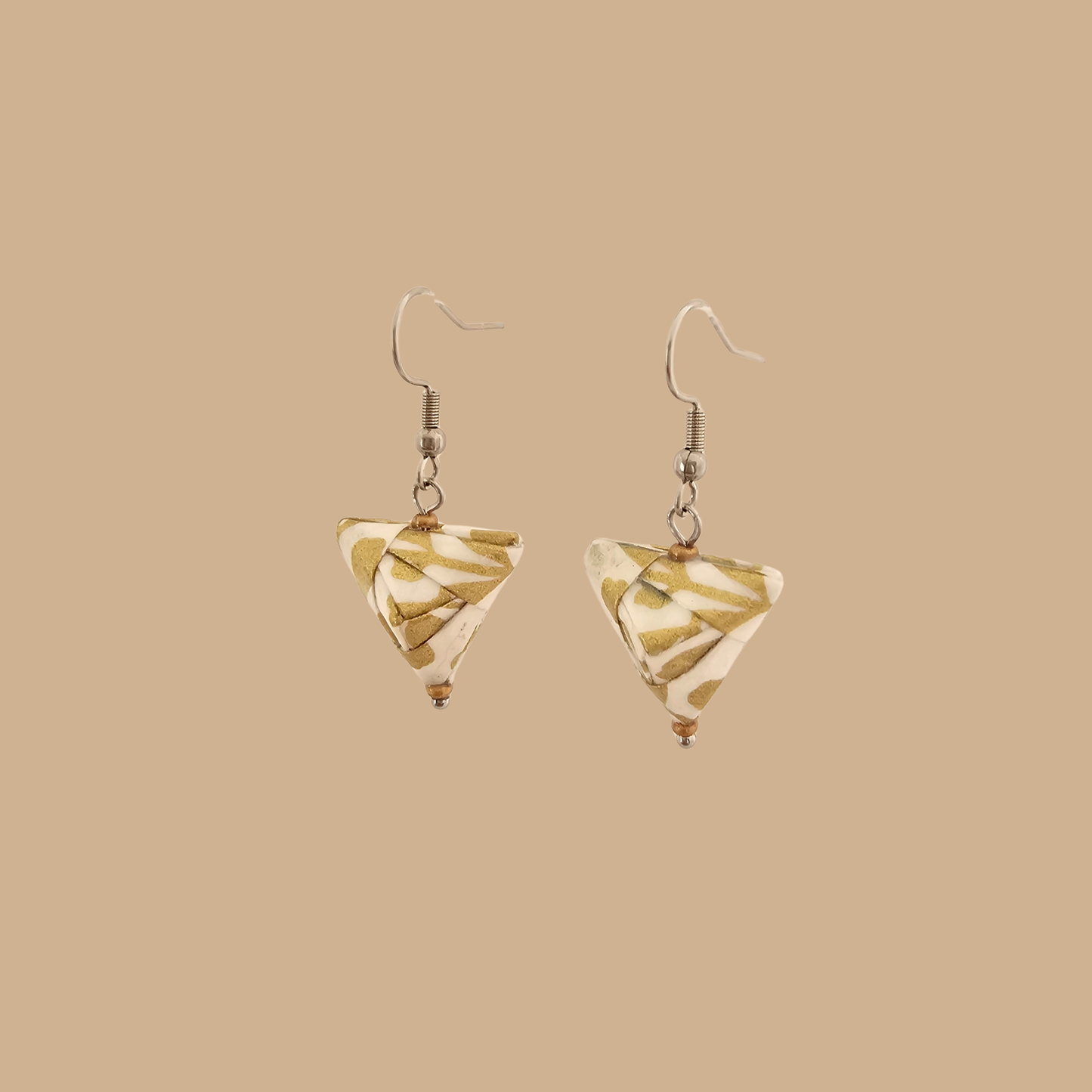 White and Gold triangle geometric origami earrings with a floral and geometric pattern on a beige background