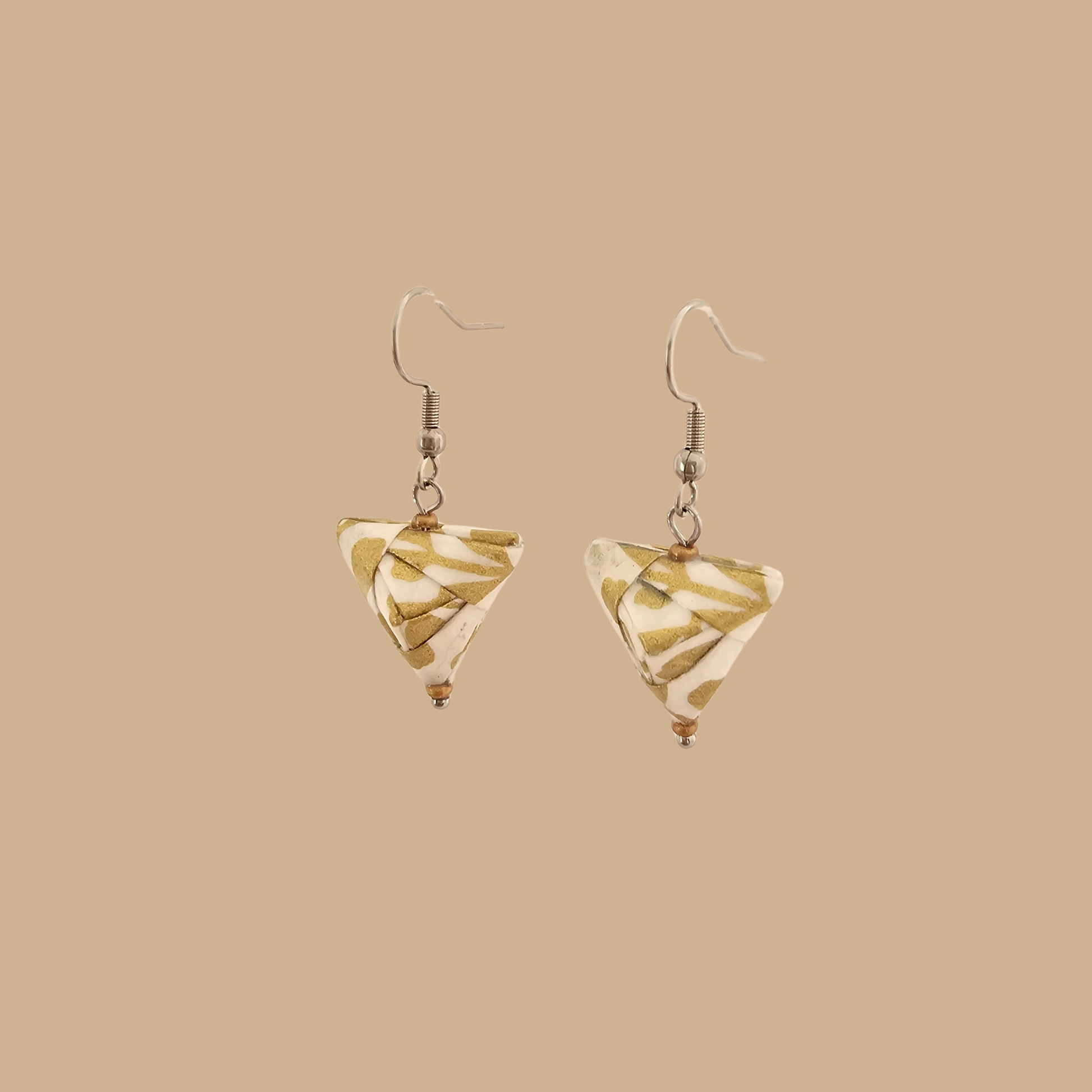 White and Gold triangle geometric origami earrings with a floral and geometric pattern on a beige background