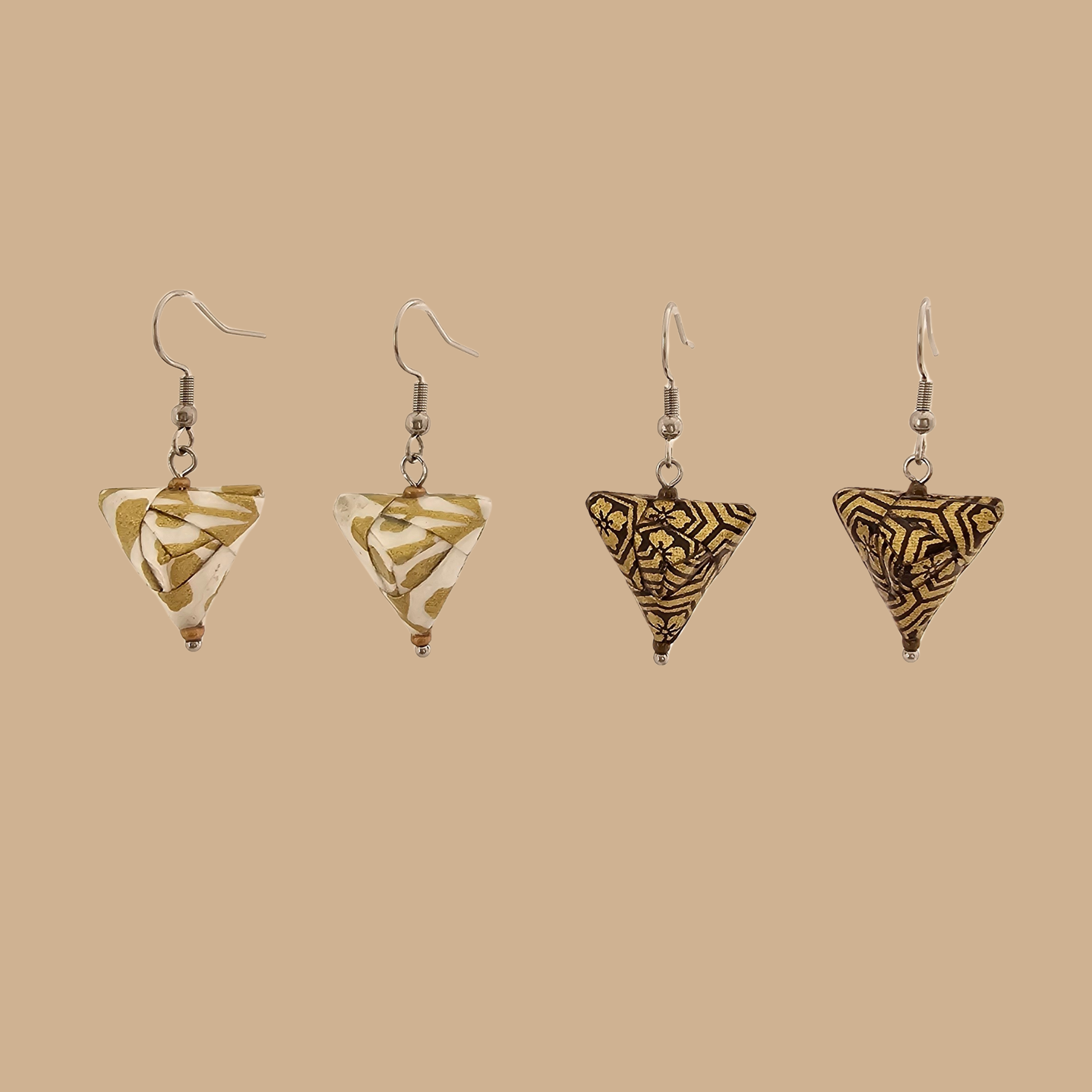White and Gold triangle geometric origami earrings with a floral and geometric pattern on a beige background